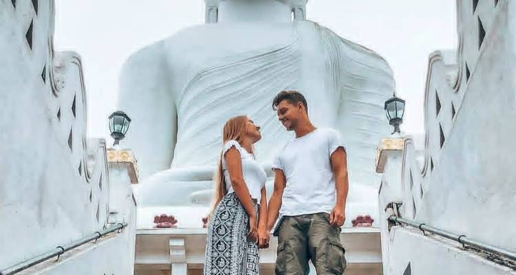Pareja de pie frente a una gran estatua de Buda.
