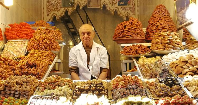 Un homme vendant une variété de bonbons et de pâtisseries au marché.