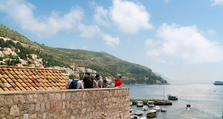 Tour group on a historic walkway overlooking the sea.