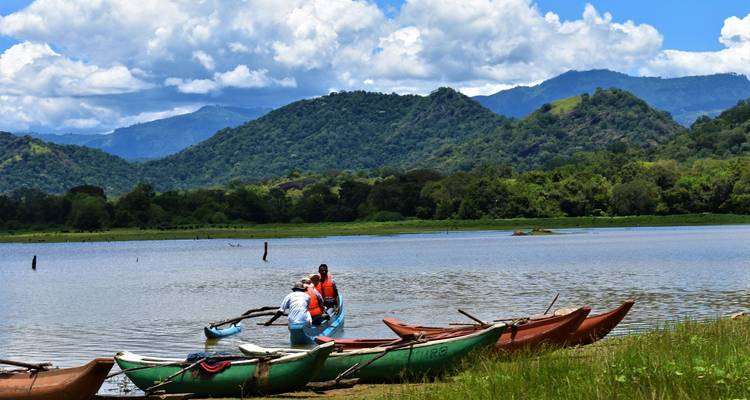 Menschen, die Kajaks an einem See mit Bergen im Hintergrund vorbereiten.