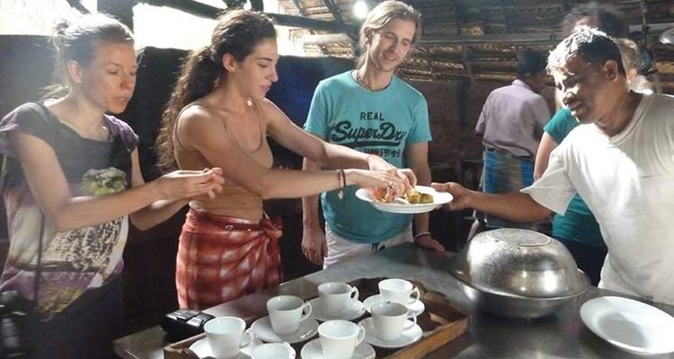 Groep mensen die zich verzamelt rond een tafel met eten.