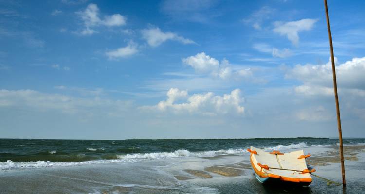 Zandstrand met een geankerde traditionele boot.