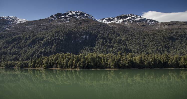 Kalm meer dat bergen en bomen weerkaatst.