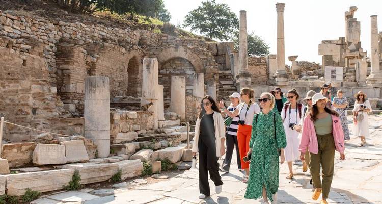 Grupo de turistas explorando ruinas antiguas bajo cielos azules.