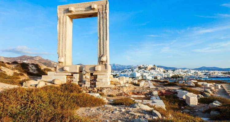 Puerta de mármol antigua con un paisaje urbano de fondo.