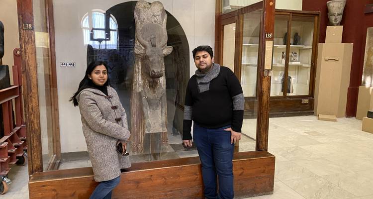 Twee mensen in een museum die bij een oud artefact staan.