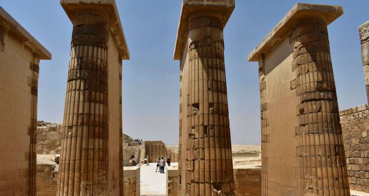 Ancient pillars with tourists exploring an archaeological site.
