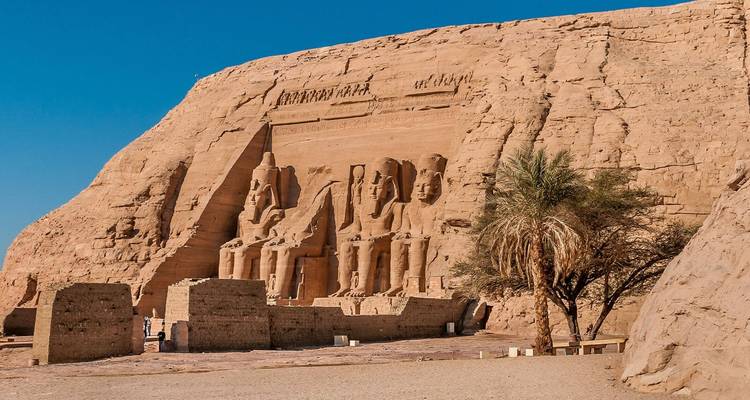 The temples of Abu Simbel carved into a rock face under a clear blue sky.