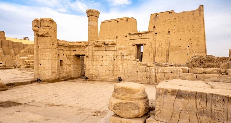 Ancient Egyptian temple with detailed carvings and a partly cloudy sky.