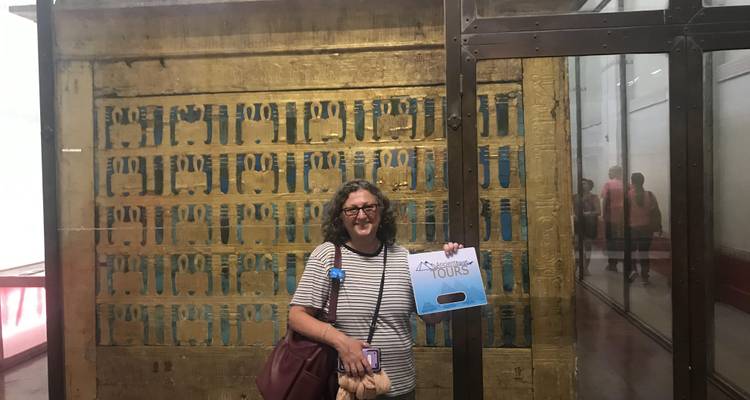 Individual holding a tour sign in a museum displaying Egyptian artifacts.