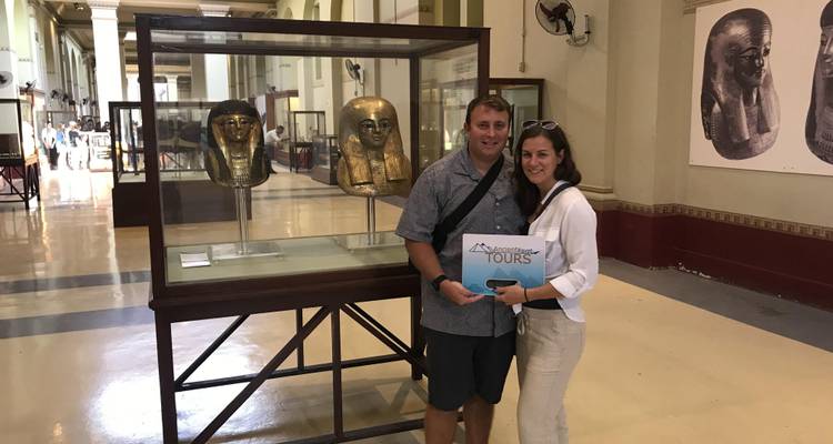 Couple holding a tour sign in a museum displaying Egyptian artifacts.