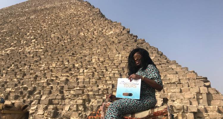 Individual posing in front of the Great Pyramid of Giza with a tour sign.