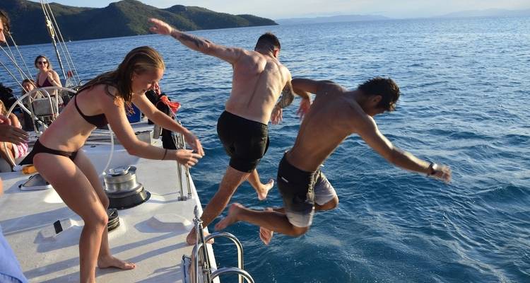 Des gens qui sautent d'un bateau dans les eaux océaniques d'un bleu éclatant.