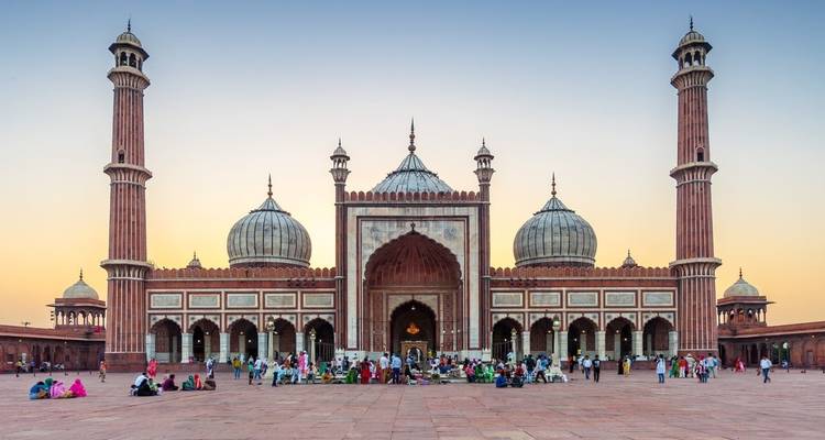 The Jama Masjid in New Delhi with people gathered in the courtyard at sunset.