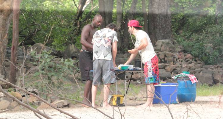 Drei Männer, die einen Picknick- oder Campingplatz in einem bewaldeten Gebiet einrichten.