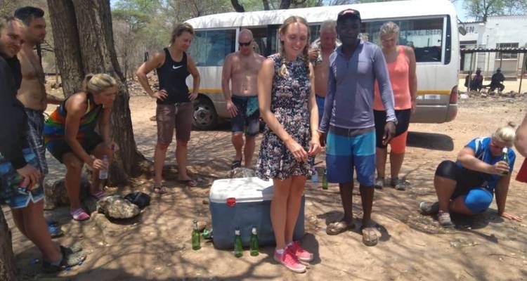 Eine Gruppe von Menschen versammelte sich um Kühlboxen neben einem Bus.