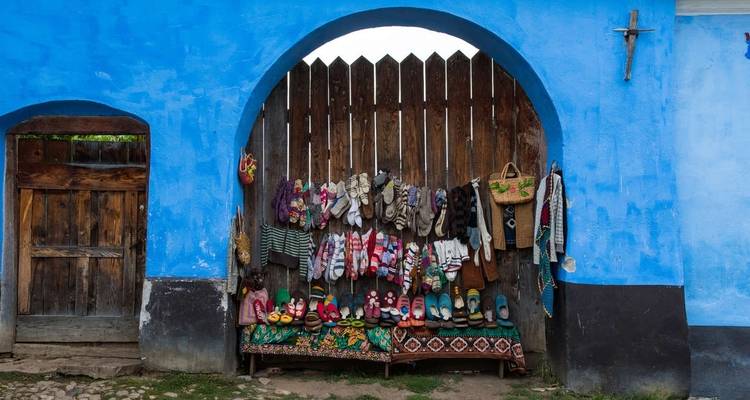 Blue wall with colorful knitted items hanging.