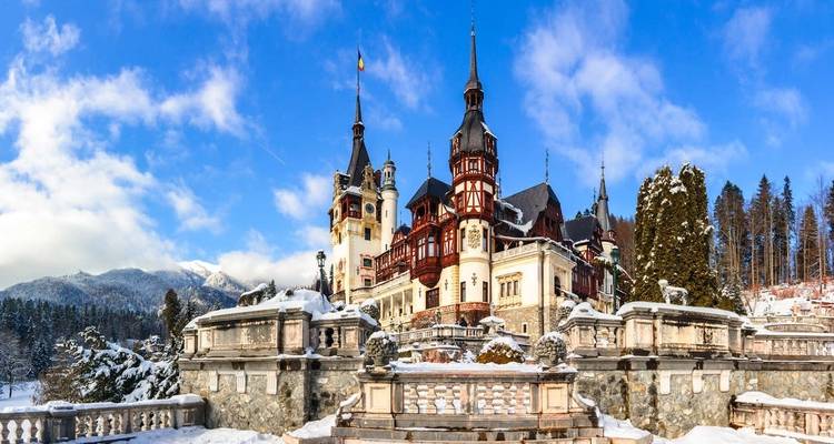 Majestic mountain castle covered in snow under a blue sky.