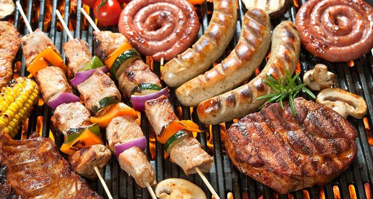 Verschiedene gegrillte Fleischsorten und Gemüse auf dem Grill.