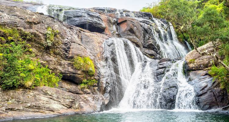 Malerischer Wasserfall umgeben von üppigem Grün.