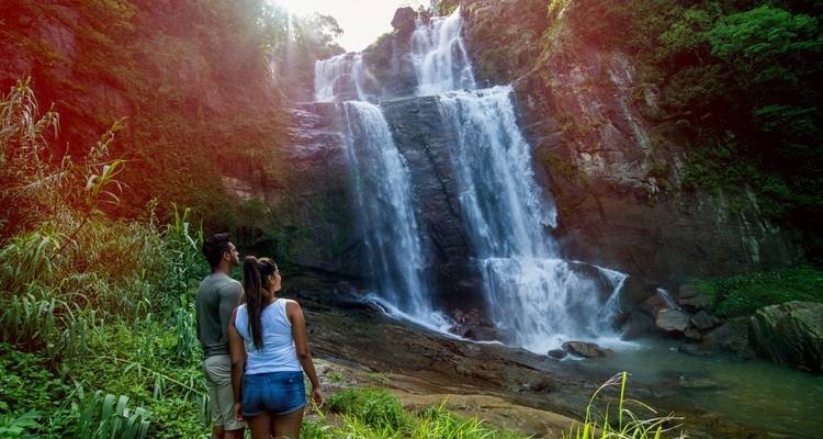 Paar bewundert einen großen kaskadenförmigen Wasserfall in einem Wald.