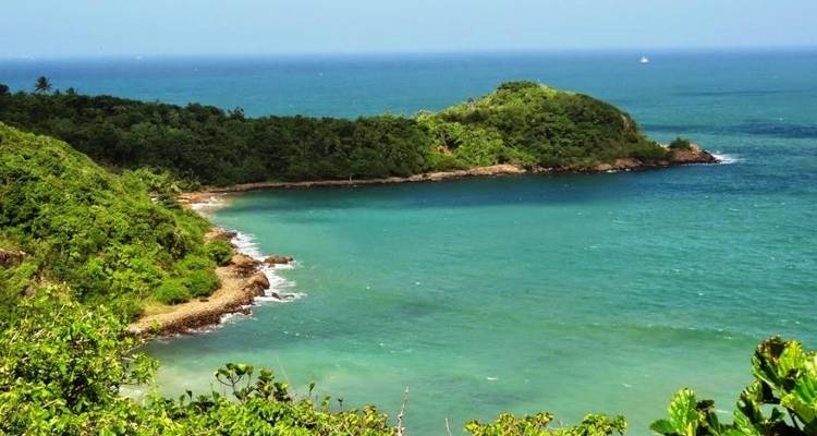 Malerische Aussicht auf ein Küstengebiet mit einer üppig grünen Halbinsel und klarem blauen Wasser.