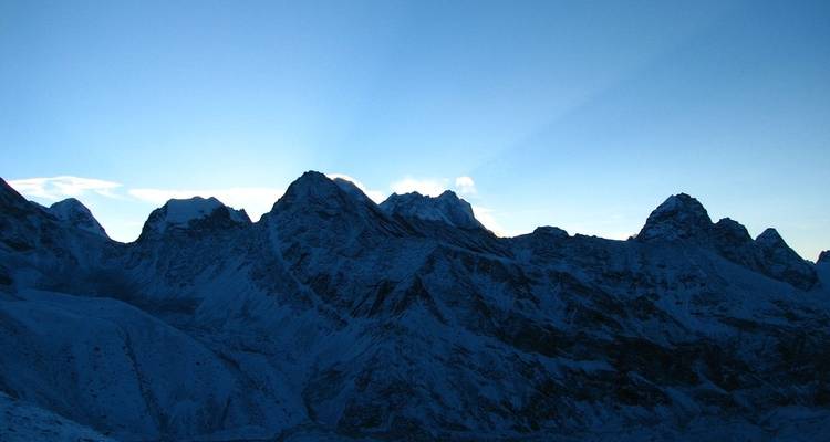 Bergketen silhouet bij zonsondergang met blauwe lucht.