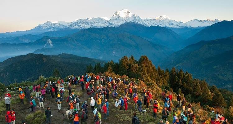 Een grote groep mensen verzamelde zich op een heuveltop met uitzicht op de bergen.