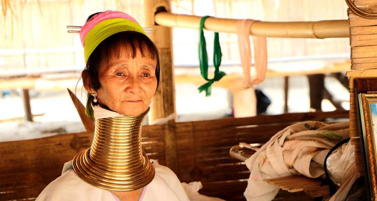 A woman dressed in traditional tribal attire, with decorative neck rings.