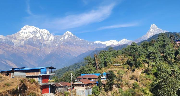 Vista de montañas cubiertas de nieve y casas rurales en un valle en Nepal.