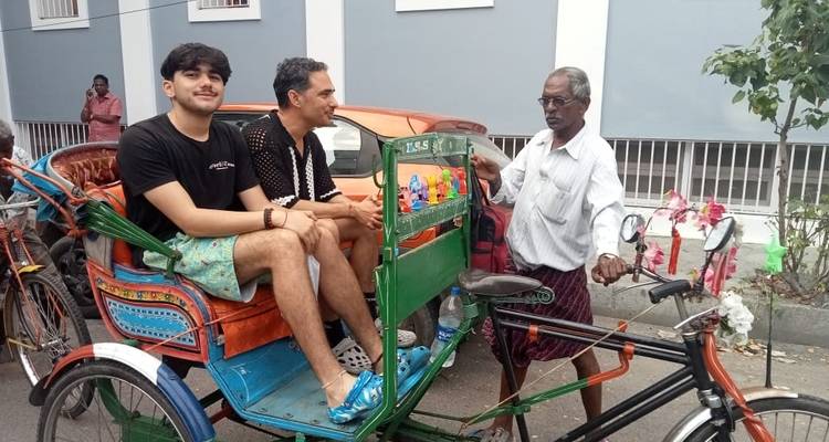 Dos hombres sentados en un rickshaw de ciclo en una calle.