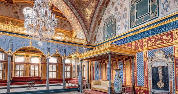 Prunkvoll dekorierter Palastinnenraum mit goldenen Akzenten und einem Kronleuchter.