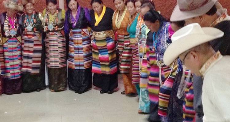 Menschen in traditioneller Kleidung stehen drinnen in einem Kreis.