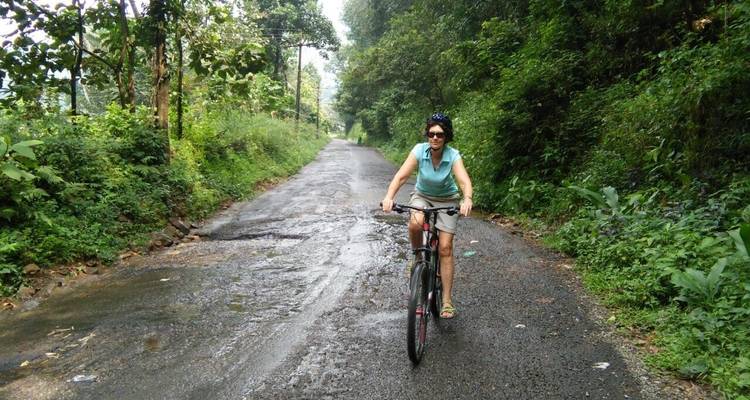 Mujer pedaleando en una carretera mojada y llena de hojas.