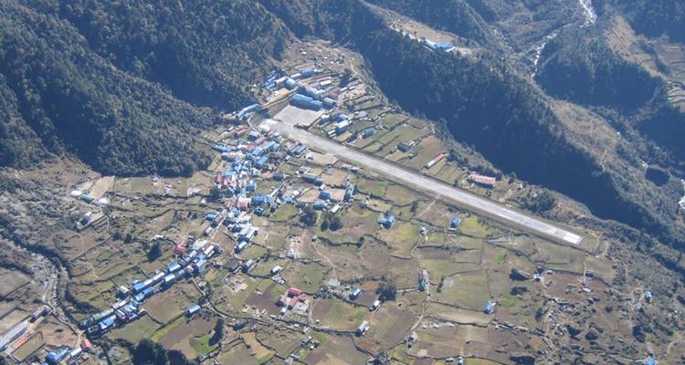 Luftaufnahme einer kleinen Stadt mit einer Flughafenlandebahn.