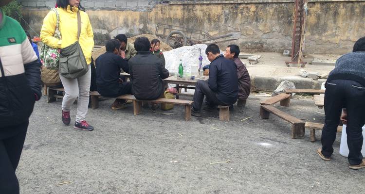 Gruppe von Männern, die mit Getränken auf einer Straße sitzen