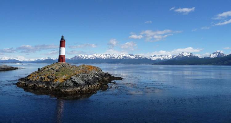 Phare sur un rocher isolé avec des montagnes en arrière-plan