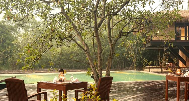 Eethoek naast een zwembad met een natuurlijke omgeving.