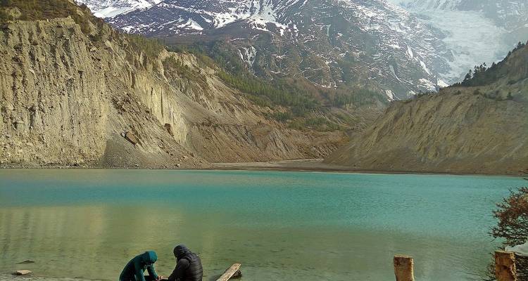 Twee mensen zittend bij een turkoois meer in een bergachtig gebied