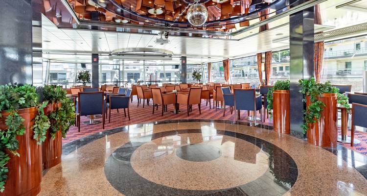 Bright panoramic lounge on board a river cruise ship with modern seating and large windows overlooking the quay.