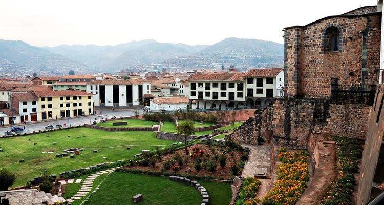 Paisaje urbano del Cusco con montañas de fondo y arquitectura histórica.