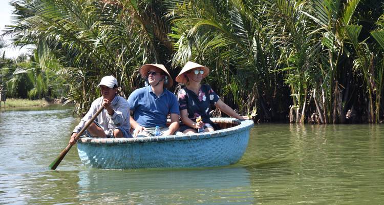 Tourists in a round boat surrounded by lush greenery.