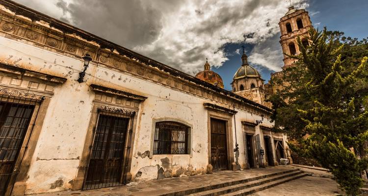 Paisaje urbano histórico con iglesia imponente y cielo dramático.