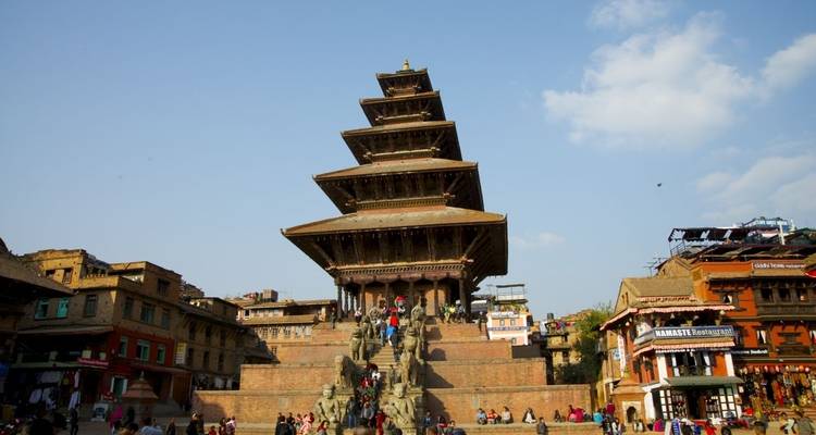 Menschen steigen die Stufen einer großen Pagode in einer belebten Straße hinauf.