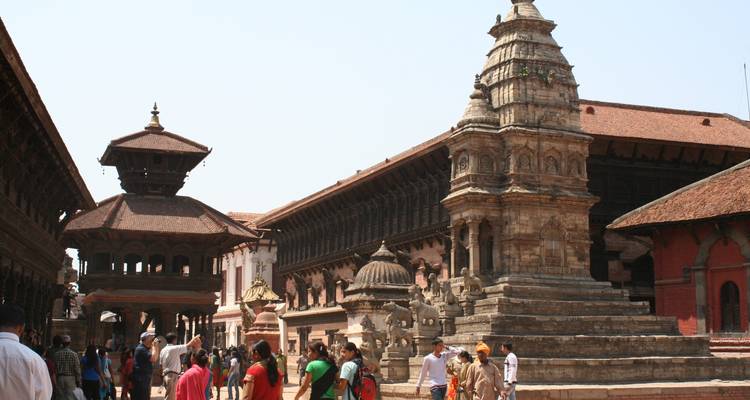 Menschenmenge, die um antike Architektur mit detaillierten Steinmetzarbeiten herumläuft.