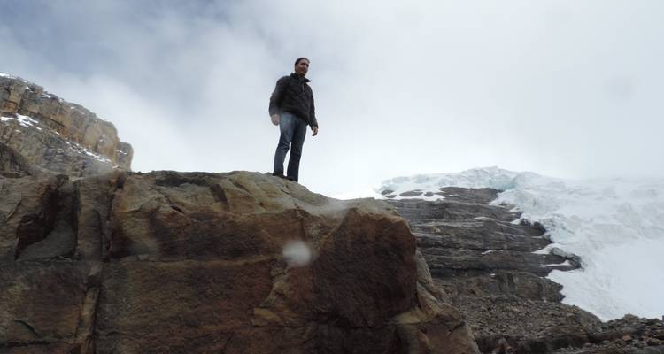 Hombre de pie sobre una roca con hielo en el fondo.