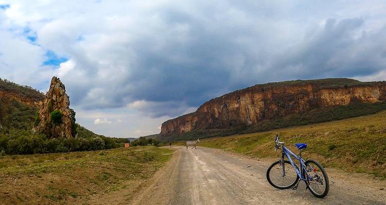 Bicycle on a dirt road with cliff formations in the background.