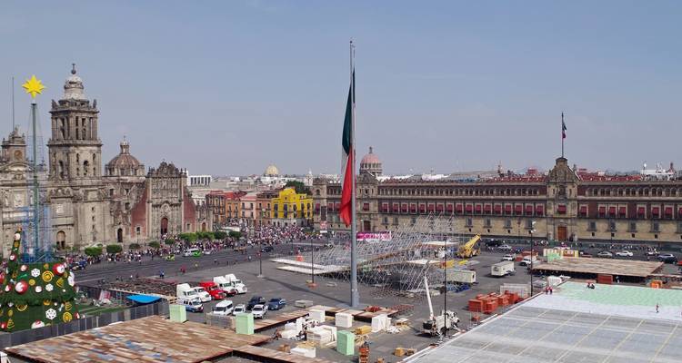 Historic city square with large flag and cathedral.