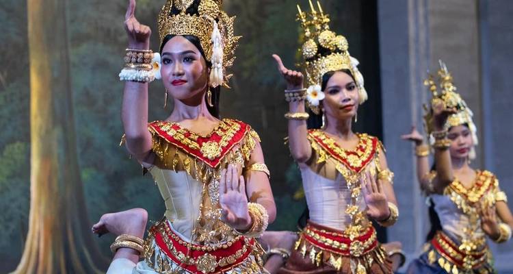 Traditionelle kambodschanische Apsara-Tänzer in aufwendigen gold- und rotgefärbten Kostümen führen anmutige Handbewegungen auf einer Innenbühne auf.