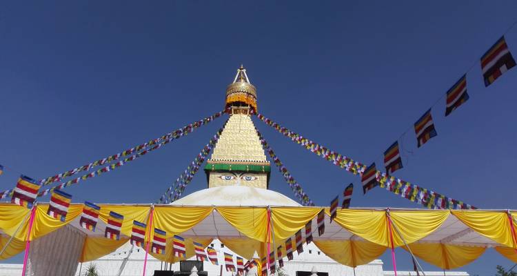 Eine große Stupa, die mit bunten Fahnen geschmückt ist, unter einem klaren blauen Himmel.